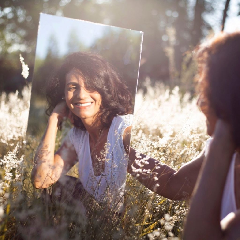 woman looking at herself in a mirror outside